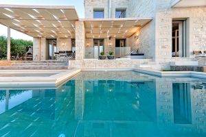 Une villa en pierre de style contemporain en Crète, située au milieu d'une oliveraie qui offre une vue imprenable sur la mer, une piscine privée, à proximité des plages locales.